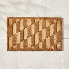 a brown door mat on the floor in front of a white wall