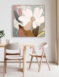 a dining room table with two chairs and a flower painting on the wall above it