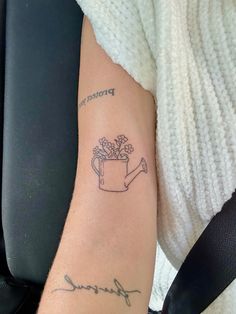 a woman's arm with a tattoo on it that reads, flower and a watering can