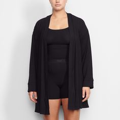 Perfect for lounging and layering over sleepwear, the Soft Lounge Robe is composed of super-soft modal ribbed fabric that drapes effortlessly in all the right places. This short robe features an adjustable self-tie belt and functional side pocket at inseam. | SKIMS Robe | Black | Soft Lounge Solid Stretch Outerwear For Loungewear, Stretch Solid Color Outerwear For Loungewear, Casual Robe For Relaxation, Open Front Loungewear Outerwear, Oversized Loungewear Cardigan, Oversized Solid Color Cardigan For Loungewear, Oversized Fall Robe For Loungewear, Oversized Fall Loungewear Robe, Solid Color Stretch Modal Sleepwear