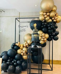 black, gold and white balloons are stacked on top of each other in a room