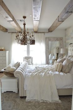 a bed room with a neatly made bed and a chandelier hanging from the ceiling