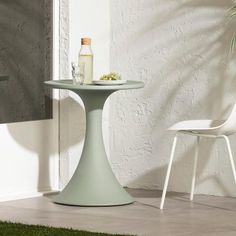 a white chair and table in front of a wall with a potted plant on it