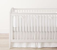 a white crib in a room with wood floors