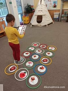 a young boy standing on top of a floor next to a pile of paper plates