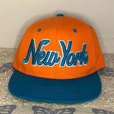 New York Snapback Hat From City Hunter Usa New Without Tags Bright Orange With Teal Lettering Size: Osfm Snap Back Color: Orange And Teal Condition: New Without Tags **Questions? Just Ask!** Please See Photos For Details And Personal Judgment On Condition Bin 1 3.4oz New York Snapback Hat Bright Style Staple Wardrobe Basics Goals Versatile Value Dandirandi Vintage Orange Snapback Hat, Orange Baseball Cap For Beach, Retro Orange Baseball Cap With Curved Brim, Orange Snapback Baseball Cap For Spring, Orange Snapback Hats For Streetwear, Trendy Orange Snapback Hat, Vintage Orange Adjustable Hat, Orange Casual Snapback Hat With Flat Bill, Casual Orange Snapback Hat With Flat Bill