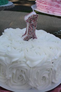 a birthday cake with white frosting and a pink number one candle on the top