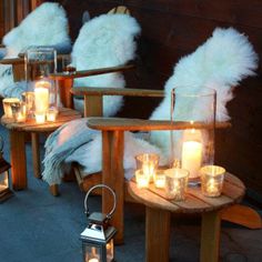 candles are lit on small wooden tables with fur pillows and throw pillows in the background