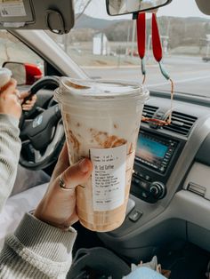 someone holding up a cup of coffee in their car