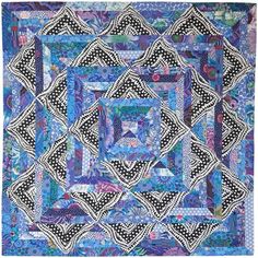 a blue and black quilt with an intricate design on the center, in front of a white