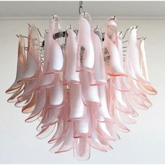 a pink chandelier hanging from a ceiling with white and pink ribbons on it