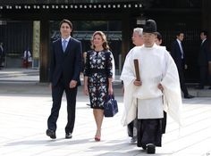 two men and a woman walking down the street with an older man in a suit