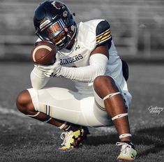 a football player kneeling on the ground holding a ball