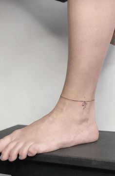 a woman's foot with a tiny cross tattoo on the side of her ankle