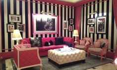 a living room with black and white stripes on the walls, pink couches and chairs