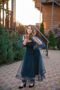 a woman in a blue dress is posing for the camera with her hands on her face