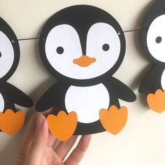 three paper penguins hanging on a line with one penguin holding the other's hand