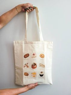 "PLEASE VISIT MY WEBSITE FOR MORE PRODUCTS! www.snapturethis.ca  The perfect lightweight reusable tote bag for coffee essentials (duh), markets, shopping, or just carrying your everyday essentials! This would make an amazing gift for a sweet treat / pastry lover! I worked with the incredible illustrator Jules (@heyoitsjules goodwellstudio)  on the original print.  Details:  Size: 15\"w x 16\"h Fabric Type: 5oz Canvas Fabric Handle: 12\" long handle Print Style: Heat Transfer  Care For Details: Hand wash cold (preferred) or cold wash on delicate cycle. DO NOT PLACE IN DRYER. Instead, let it air dry by placing it on a flat surface and realigning the straps so they don't dry wrinkled. Canvas material shrinks when you wet it, please avoid washing often and instead spot clean as needed.  How to Large Everyday Canvas Gift Bag, Daily Canvas Tote Bag For Gifts, Coffee Essentials, Pop Up Market, Gift Totes, Cafe Logo, Graphic Tote, Coffee Gifts, Bag Canvas