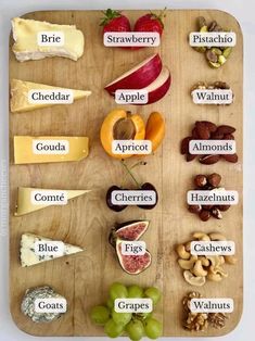 a wooden cutting board topped with lots of different types of cheeses and fruit on it