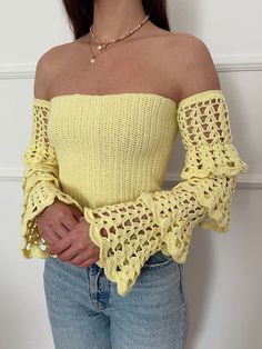 a woman wearing a yellow top with crochet sleeves and a choker necklace