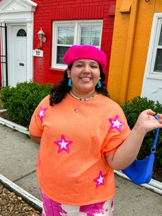 Bring on the glitz and glam with this oversized tee! This orange tee features pink stars that make you feel like a super star!!! Keep it casual with a pair of jeans or colorful pants, or dress it up with a pink skirt! This tee looks great with pinks, yellows, and blues! Oversized fit Style with jeans, colorful pants, or a cute skirt! This shade of orange looks great with pinks, blues, and yellows! True to size with an oversized fit 50% POLYESTER 37% COTTON 13% RAYON Imani is 5'3 and wearing a si Colorful Pants, Orange Star, Orange Tees, Pink Power, Colored Pants, Neutral Outfit, Super Star, Pink Stars, Glitz And Glam