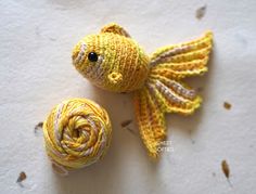 a small yellow fish next to a ball of yarn