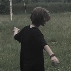 a young boy standing in the middle of a field