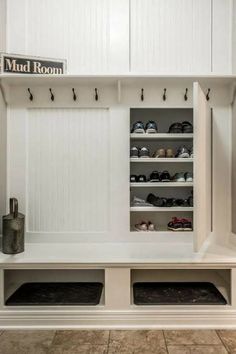 a mud room with white cabinets and shoes