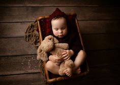 a baby sitting in a chair holding a teddy bear