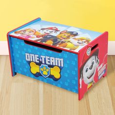 a toy box with paw patrol characters on it sitting on the floor in front of a yellow wall