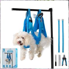 a white dog hanging from a blue harness with tools attached to it's sides