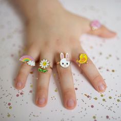 a child's hand with four rings on it, including an animal and sunflower