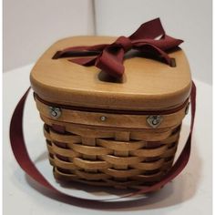 a wooden basket with a red ribbon tied around the top and bottom, sitting on a white surface