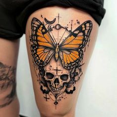 a woman's thigh with a butterfly and skull tattoo on it