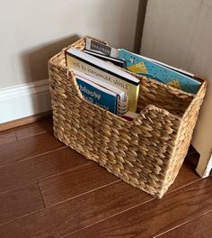 a wicker basket with books in it on the floor