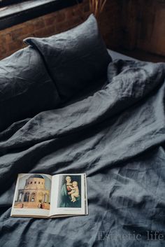 an open book sitting on top of a bed next to pillows and pillowcases