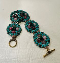 a blue and pink beaded bracelet on a white tablecloth with a gold key hanging from the clasp