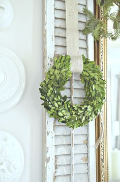 a wreath hanging on the side of an old shuttered door in front of a mirror