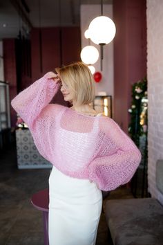 a woman wearing a pink sweater and white skirt