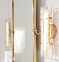 two lights on the wall next to each other in front of a mirror and light fixture