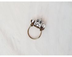 a ring with a house on it sitting on top of a white table next to a pair of scissors