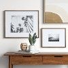 a wooden table topped with a vase filled with flowers next to pictures on the wall