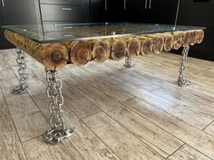 a table made out of wood with chains on the legs and glass top, in a kitchen