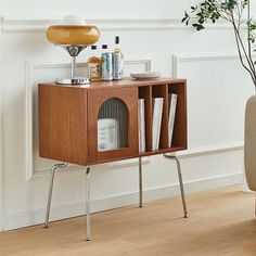 a small wooden cabinet with books and magazines on it next to a chair in a living room