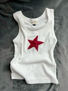 a white shirt with a red star on the front and bottom, sitting on a bed