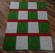 a green and white blanket on the floor with red trimmings, which has been crocheted to look like christmas trees