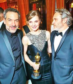 three people in tuxedos posing with an oscar for best supporting actor and actress