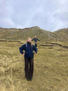 two people standing in a field with mountains in the background