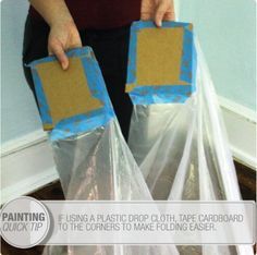 a person holding two plastic bags with blue tape on them and the words, using plastic drop cloth, tape cardboard to corners to make folding easier