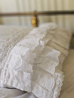 an image of white linens on a bed with lace trim around the edges and pillows